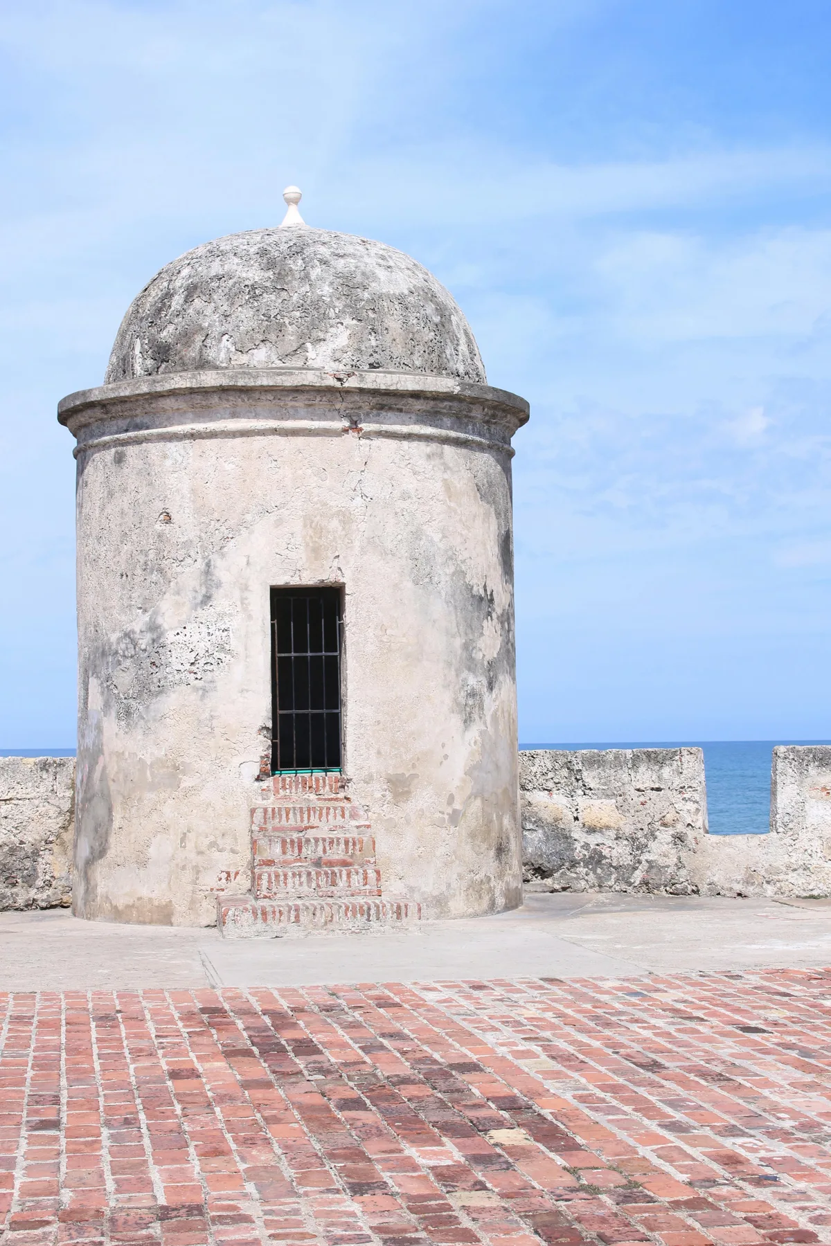 A historic stone sentry tower with a sea view under a clear blue sky.