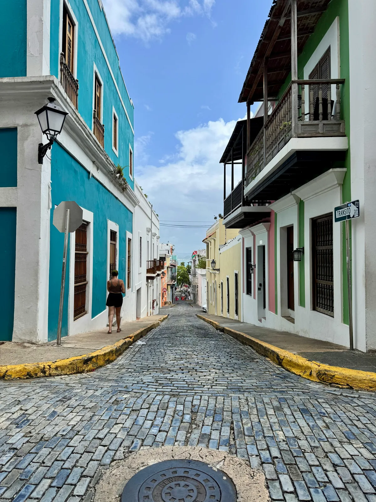 Charming view of a vibrant street in Old San Juan, featuring colorful buildings and a cobblestone path.