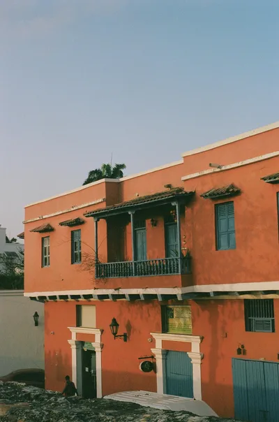 A vibrant colonial building with orange facade and blue windows in Cartagena, Colombia.