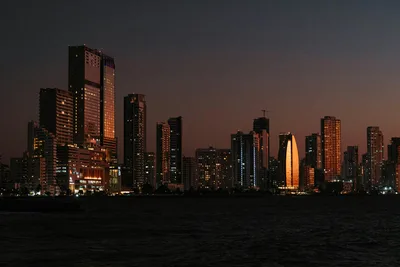 Explore the illuminated skyline of Cartagena de Indias against a serene dusk sky, featuring iconic skyscrapers.