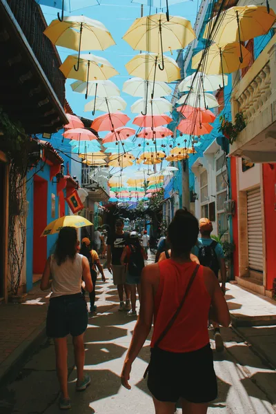Vibrant street with hanging umbrellas in Cartagena, bustling with tourists.