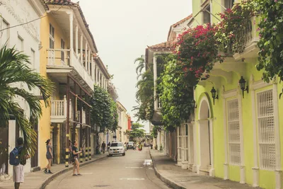 A picturesque street lined with colorful colonial buildings and lush greenery, featuring a relaxed urban atmosphere.