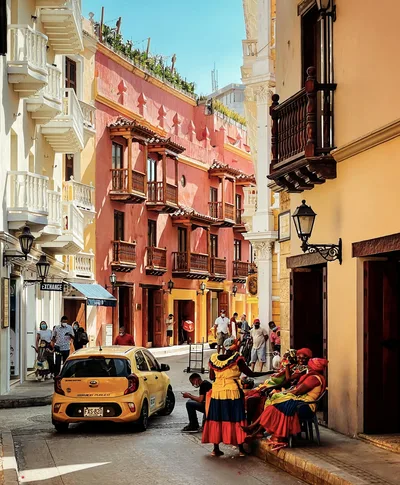 Vibrant street in Cartagena with people in traditional dress, sunny atmosphere.