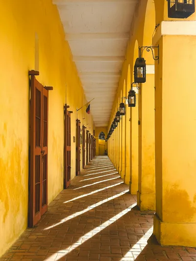 Sunlit corridor with yellow arches in Las Bovedas, Cartagena showcasing colonial architecture.