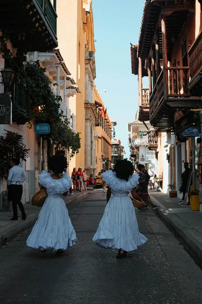Two women in white dresses perform on a charming street in Cartagena, Colombia.