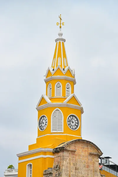 Vibrant yellow clock tower in Cartagena against a cloudy sky, showcasing colonial architecture.